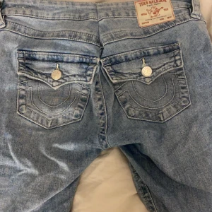 Blå jeans Joey Low Rise Flare - Säljer ett par snygga blå jeans från True Religion i modellen Joey Low Rise Flare. De har en låg midja och en utsvängd bootcut-stil. Perfekta för en avslappnad look med en touch av retro. Storlek 29 men insydda till ca 27,28 (syns inte på utsidan och går att sprätta upp)💝