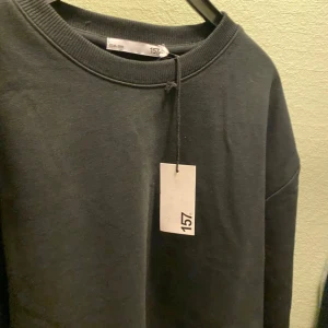 Svart tröja från 157 - Säljer en svart tröja från 157 i storlek XS. Den är i nytt skick och har en enkel, stilren design med långa ärmar och rund hals. Perfekt för en avslappnad look eller att mysa i hemma. 