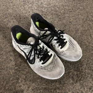 Vita och svarta Nike sneakers - Säljer ett par vita och svarta Nike sneakers i bra skick. De har en snygg design med svart snörning och en ventilerande ovandel. Perfekta för träning eller vardagsbruk. Sköna och lätta att bära! Stl 38. 