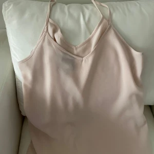 Beige linnetopp från Vero Moda - Säljer en stilren beige linnetopp från Vero Moda. Toppen är ärmlös med smala axelband och har en enkel, elegant design. Perfekt för sommardagar eller som ett basplagg i garderoben. Passar både till vardags och festliga tillfällen.