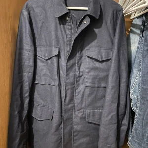 John henric overshirt  - Säljer en stilren mörkblå overshirt i mycket bra skick. Den har långa ärmar och praktiska fickor framtill. Perfekt för höst och vår, och funkar både till vardags och lite finare tillfällen. Passar bra över en t-shirt eller tröja. 9/10 storlek L. Pm för fler bilder 