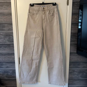 Beige byxor från NA-KD - Beige byxor från NA-KD med klassisk femficksdesign och knappgylf. Perfekta för en stilren look med en rak passform som ger en avslappnad känsla.