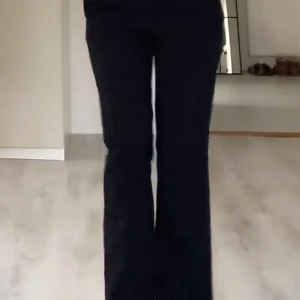Svarta lågmidjade byxor från Nelly - Säljer ett par stilrena svarta lågmidjade byxor från Nelly. De har en rak passform och är perfekta för både vardag och fest. Storlek 36 men har lagt in ett skosnöre som kan göra de mindre 