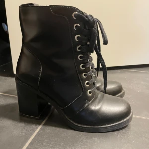 Svarta boots med klack och snörning - Snygga svarta boots med klack och snörning. De har en praktisk dragkedja på sidan för enkel på- och avtagning. Perfekta för en stilren look.