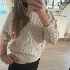 Beige stickad tröja - Säljer en superfin beige stickad tröja med ett snyggt mönster. Den har trekvartsärmar och ribbade muddar vid ärmslut och nederkant. 