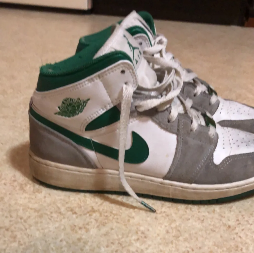 Snygga Nike Air Jordans i vitt och grönt med grå detaljer. Skorna har snörning och en klassisk hög design. Perfekta för en sportig look.. Kengät.