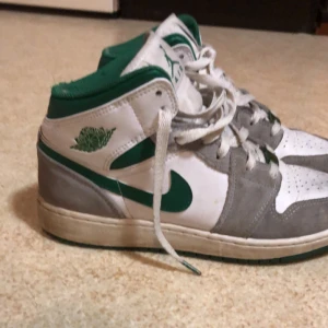 Air Jordan 1 Low  - Snygga Nike Air Jordans i vitt och grönt med grå detaljer. Skorna har snörning och en klassisk hög design. Perfekta för en sportig look.