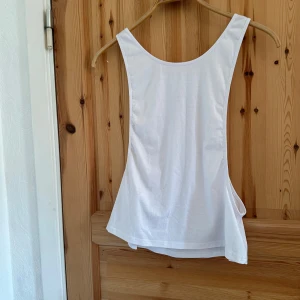 Vit linnetopp från Shein - Säljer en vit linnetopp från Shein med texten 'WORK WORK WORK WORK' i svart på baksidan. Toppen är ärmlös och tillverkad i polyester, perfekt för en aktiv dag.