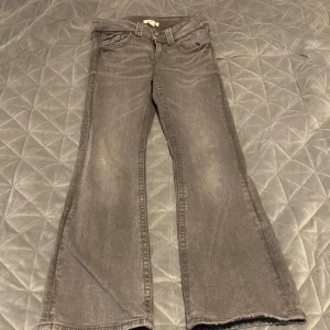 Grå bootcut jeans från Gina Tricot - Snygga grå bootcut jeans från Gina Tricot. De har en klassisk femficksdesign och dubbla knappar i midjan. Perfekta för en avslappnad stil med en touch av retro.
