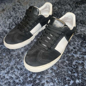 Svarta och vita sneakers från Valentino - Snygga svarta och vita sneakers från Valentino med klassisk design. Skorna har snörning och är dekorerade med nitar på sulan. Perfekta för en stilren look.