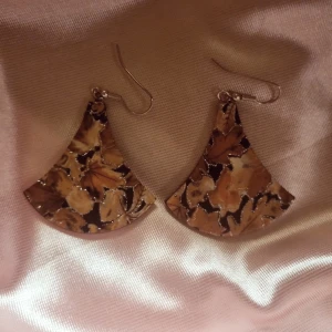 Mönstrade örhängen i höstfärger - Snygga 70-tals örhängen med ett unikt mönster i varma höstfärger. De har en bred, svängd form och hängs enkelt i öronen med krokar. Äkta vintage 💗