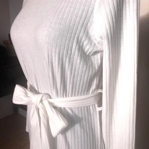 Lång klänning med polo  - Väldigt vacker klänning med polo krage och skärp som markerar midjan. I nyskick med lapparna kvar. Längd ca 120cm. Ärmlängd ca 62cm.