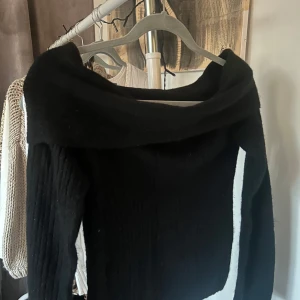 Svart offshoulder tröja från Boohoo - Snygg svart offshoulder tröja från Boohoo. Perfekt för en stilren look med sin ribbade design och långa ärmar. Passar bra till både jeans och kjol. Ett måste i garderoben för den som gillar trendiga plagg! Helt ny!