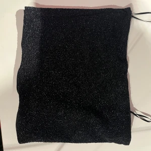 Svart glittrig tubtopp från Gina Tricot - Snygg svart glittrig topp från Gina Tricot i storlek XS. Perfekt för att lysa upp din outfit med lite glitter. 
