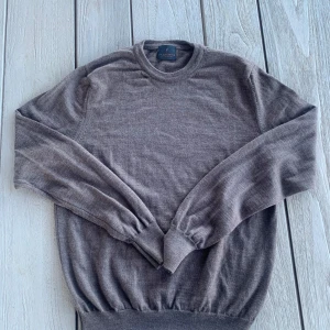 Brun merinoulltröja från La Chemise - Säljer en stilren brun tröja från La Chemise i 100% merinoull. Perfekt för kyligare dagar med sin mjuka och värmande kvalitet. Tröjan har långa ärmar och en klassisk rund halsringning. Tillverkad i Italien.                   Liten i storleken, sitter som xs