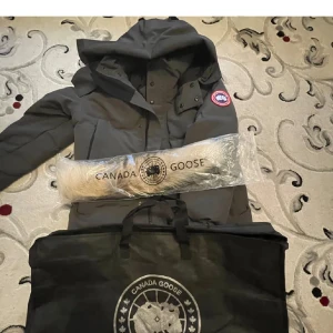 Grå  dunjacka från Canada Goose - Säljer en grå dunjacka från Canada Goose med pälsdetalj på huvan. Tveka inte att skicka ett sms 🤪