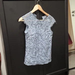 Ljusblå spetströja - Tröjan är ärmlös och har en smickrande passform. Perfekt för sommarens festligheter!