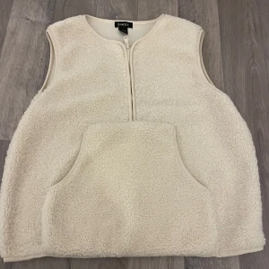 Vit fluffig kofta från Lindex - Mysig vit fleeceväst från Lindex med dragkedja framtill och en stor ficka. Perfekt för kyliga dagar när du vill hålla dig varm och bekväm.