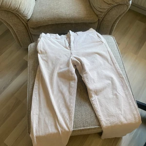 Manchester byxor - Snygga randiga byxor i ljusa färger, perfekta för en avslappnad stil. Byxorna har en rak passform och är tillverkade i mjuk bomull för extra komfort. De har en klassisk midwaist och stängs med dragkedja. 