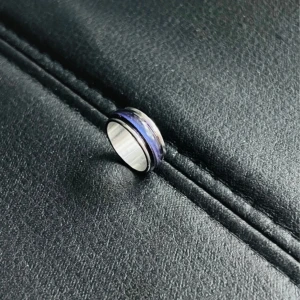 Förtrollande blå glasring i stainless steel - Ringen är tillverkad av rostfritt stål och har en inre diameter pả 18 mm. Den är utsmyckad med ett glasband i en djup, blå nyans som ger ringen ett elegant och lugnt utseende. Glasets färg har en sofistikerad effekt, vilket gör denna ring till ett perfekt val för den som föredrar subtila men uttrycksfulla accessoarer.