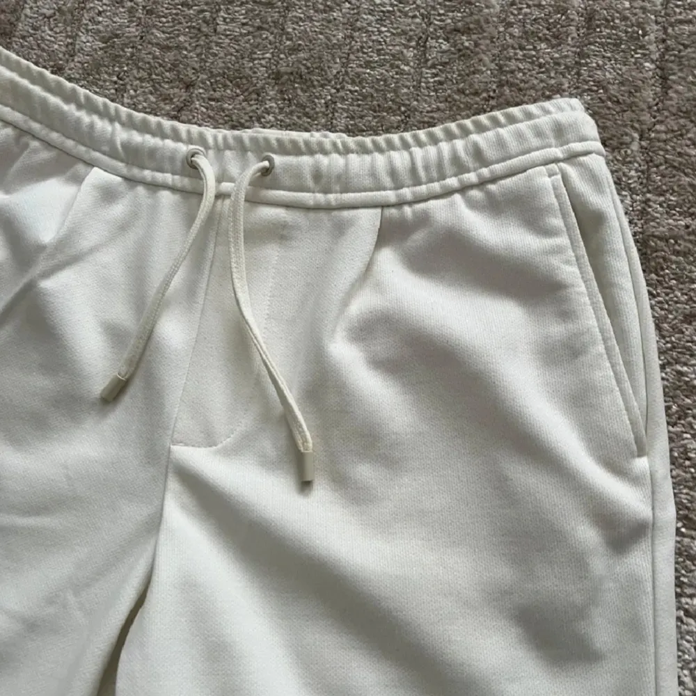 Snygga vita shorts med elastisk midja och snörning för en bekväm passform. De har fickor på sidorna och uppvikta benslut för en stilren look. Perfekta för varma dagar.. Shortsit.