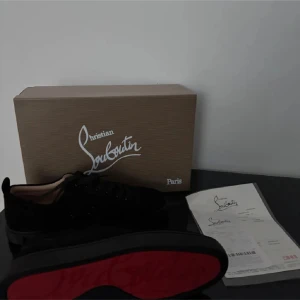 Christian Louboutin Skor - Snygga svarta sneakers från Christian Louboutin med den ikoniska röda sulan. Skorna har en stilren design med snörning och är tillverkade i mocka. Perfekta för den som vill ha en lyxig touch i vardagen.