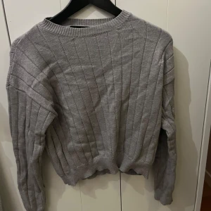 Grå ribbad tröja från Shein - Säljer en stilren grå ribbad tröja från Shein. Tröjan har en klassisk rund hals och långa ärmar, perfekt för kyligare dagar. Den är mjuk och bekväm, vilket gör den till ett mångsidigt tillskott i garderoben. Säljer den då jag fick den av min syster då hon aldrig använde den, inte använd mycket