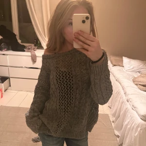 grå stickad tjocktröja  - säljer en stickad grå tröja med hål på framsidan som jag verkligen tycker ger lite mer ”djup” i outfiten. den går att både off-shoulder och vanligt. super fin och han använts fåtal gånger. 