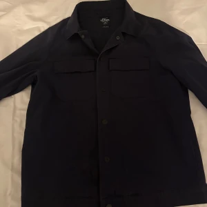 Mörkblå overshirt  från s.Oliver - Snygg mörkblå jacka från s.Oliver med knappar framtill och två bröstfickor. Perfekt för en stilren look. Jackan har en klassisk krage och är långärmad. Andvänd fåtal gånger.