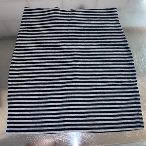 Randig kjol från H&M Divided - Snygg randig kjol från H&M Divided i svart och grått. Kjolen har en enkel och stilren design med horisontella ränder. Perfekt för en avslappnad look.