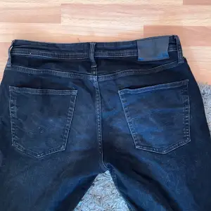 Säljer ett par svarta tapered jeans från Jack & Jones, modell Mike. De har en klassisk femficksdesign och stängs med dragkedja och knapp. Perfekta för en stilren look.
