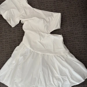 Vit oneshoulder klänning - Såååå fin vit oneshoulder klänning med en volangdetalj i kjolen. Perfekt för sommaren och studenten. Aldrig använd! 