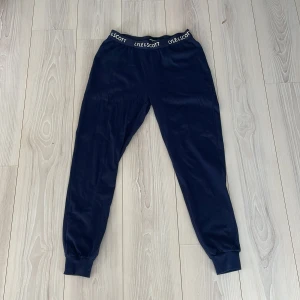 Mörkblå mjukisbyxor från Lyle & Scott - Snygga mörkblå mjukisbyxor från Lyle & Scott med elastisk midja och logotypdetaljer. Perfekta för en avslappnad stil. Tillverkade i en mjuk bomullsblandning för extra komfort. Bra pris!👀
