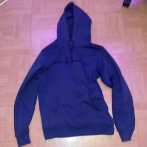 Mörkblå hoodie från Sail Racing - Säljer en mörkblå hoodie från Sail Racing. Den har en klassisk design med en stor ficka framtill och justerbar huva. Perfekt för kyliga dagar och avslappnade stunder. Passar bra till jeans eller träningsbyxor. Jätte bekvämt och ha på sig! Ganska använd, hör gärna av dig👍. Ny pris 999!
