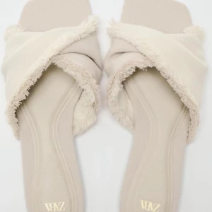 Beige sandaler med fransdetaljer - Snygga beige sandaler med korsade remmar och fransdetaljer. Perfekta för en avslappnad stil med en touch av elegans.