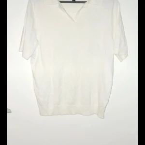 Vit kortärmad pikétröja - Säljer en stilren vit pikétröja med korta ärmar och klassisk krage. Perfekt för en avslappnad men ändå snygg look.