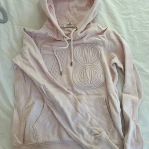Ljusrosa hoodie med broderad detalj - Säljer en ljusrosa hoodie, har känguruficka och justerbar huva med snören. *färgen är babyrosa, ser bra ut irl jämfört med bilden 