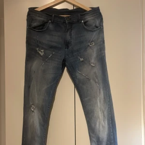 Blå slim jeans med slitningar - Snygga blå jeans med slitningar och en modern look. De har en klassisk femficksdesign och en bekväm passform. Perfekta för en avslappnad stil. Slim Jeans i storlek. Original pris 1700kr