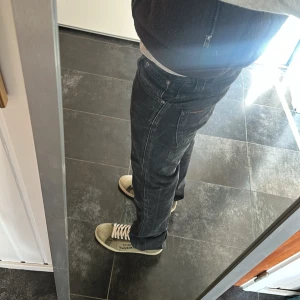 Svarta slim jeans från Nudie Jeans - Snygga svarta slim jeans från Nudie Jeans i modellen Slim Jim. Tillverkade av 100% bomull med en klassisk femficksdesign och knappgylf. Perfekta för en stilren look. W31 L36