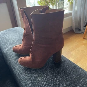 Bruna mocka boots med klack - Snygga bruna boots i mocka med en hög klack och dragkedja på sidan. Perfekta för att ge en stilren touch till din outfit.