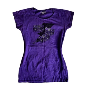 Lila t-shirt med blixttryck - Cool lila t-shirt med ett unikt blixttryck och kassettband på framsidan. Perfekt för dig som vill sticka ut med en retrovibe.