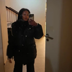 Svart pufferjacka - Säljer en svart pufferjacka med dragkedja och knappar. Jackan har en oversized passform och långa ärmar, perfekt för kalla dagar. Den är både stilren och praktisk med stora fickor framtill.