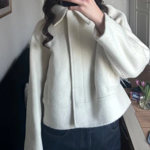 Vit jacka - Säljer en stilren vit jacka. Jackan har en normal passform och långa ärmar, perfekt för kyligare dagar. Den är enkel att matcha med olika outfits och ger en elegant touch.