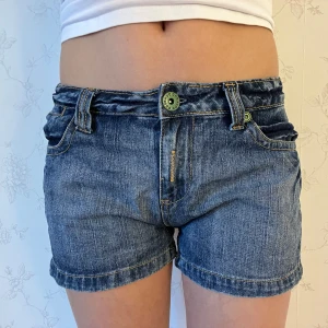 Blå jeansshorts  - Snygga blå jeansshorts med gröna dragkedjor på bakfickorna. Shortsen har en klassisk femficksdesign och knappgylf. Kolla gärna in mina andra shorts💕