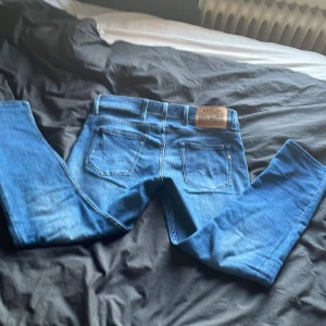 Blå jeans från Replay - Snygga blå jeans från Replay med klassisk femficksdesign och en snygg läderpatch baktill. Perfekta för en avslappnad stil.