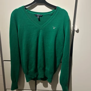 Grön tröja från GANT - Säljer en snygg grön tröja från GANT med v-ringning. Tröjan har långa ärmar och ribbade muddar vid ärmslut och nederkant. 