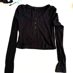 Svart topp med knappar - Snygg svart  topp med långa ärmar och tre knappar framtill. Aldrig använd för tyckte den var för liten. 