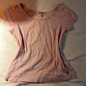 Rosa kortärmad topp från Esprit - Säljer en söt rosa topp från Esprit. Toppen är i mjukt bomullsmaterial och har en liten metalllogga vid fållen.