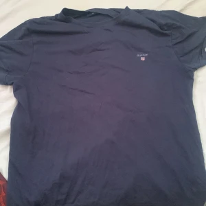 Mörkblå t-shirt från GANT - Säljer en stilren mörkblå t-shirt från GANT med liten logga på bröstet. Perfekt för en avslappnad look. Passar bra till jeans eller shorts.