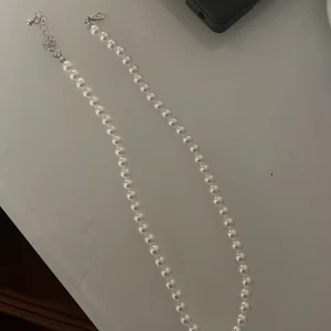 Pärlhalsband med justerbar kedja - Elegant pärlhalsband med vita pärlor och en justerbar kedja i silverfärg. Perfekt för att ge en klassisk touch till din outfit. Lätt att matcha med andra smycken.